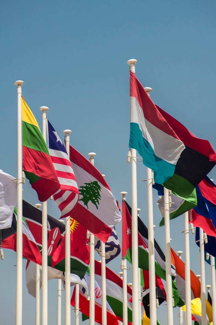 about-02 A vibrant array of international flags waving against a clear blue sky, symbolizing global unity.