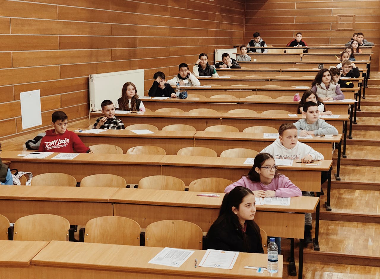 contact-img Students seated in rows in a lecture hall, focused on their exams.