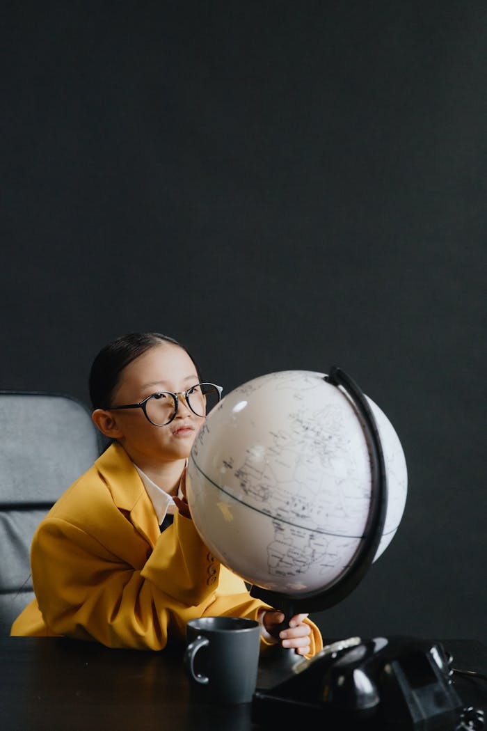 Curious child in glasses exploring a globe, fostering a love for geography.